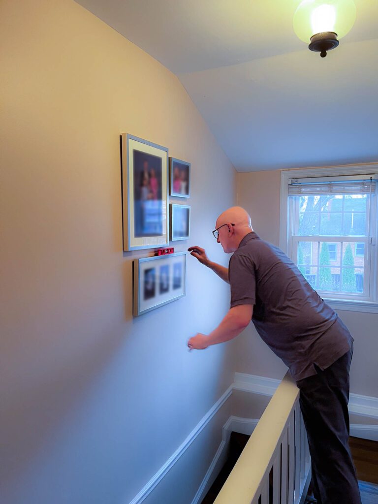 checking level on gallery wall portraits after install | Lisa Maco DC familyl photography