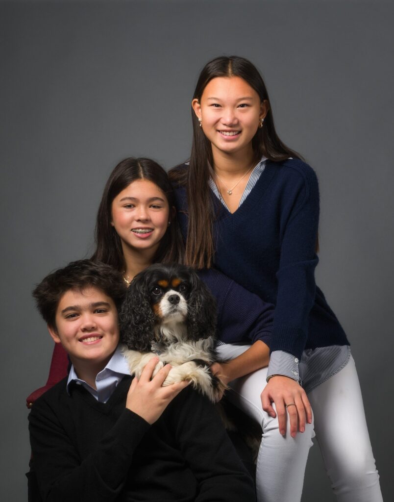 Three smiling teens and their dog posed together during a professional DC family photography session