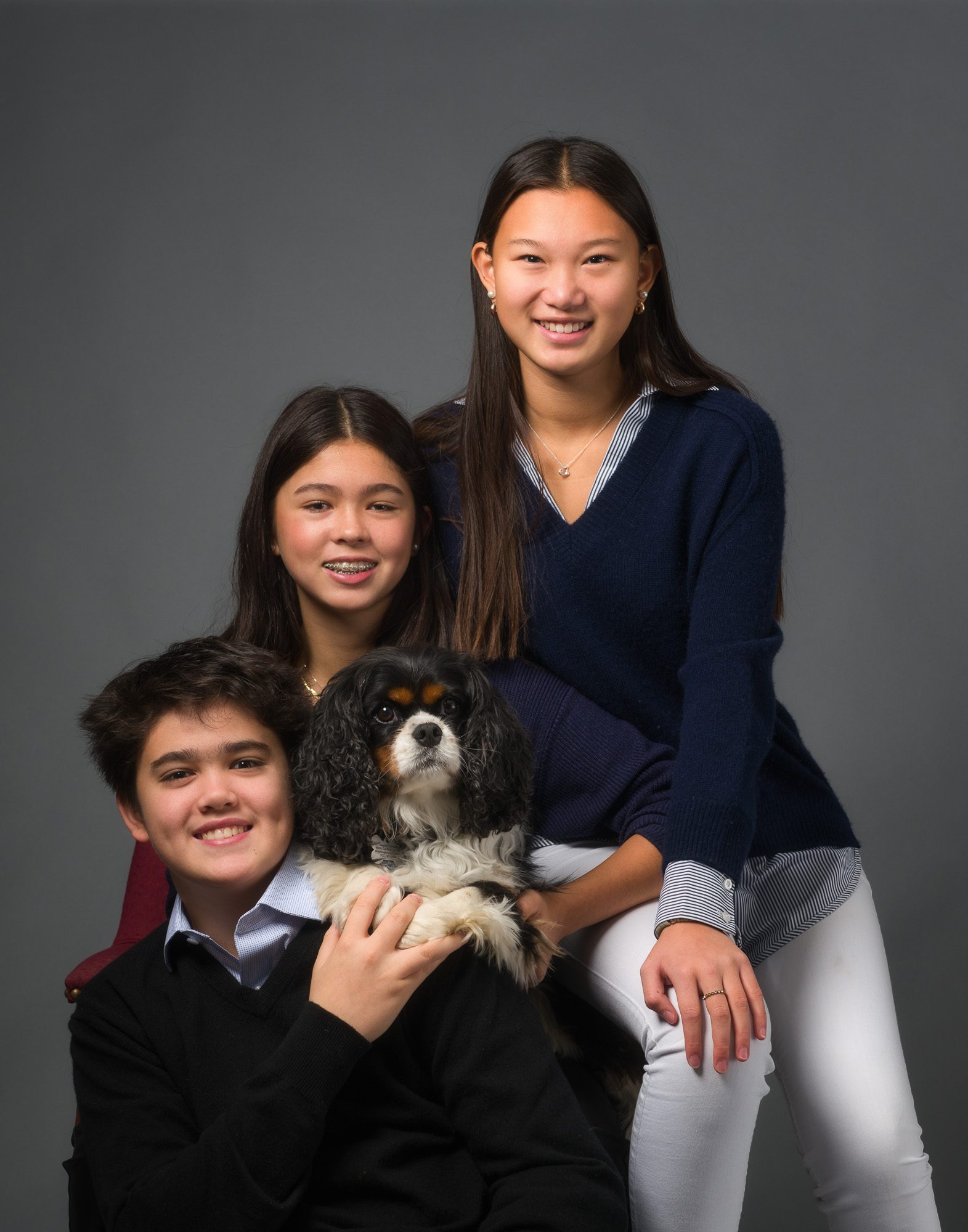 Three smiling teens and their dog posed together during a professional DC family photography session