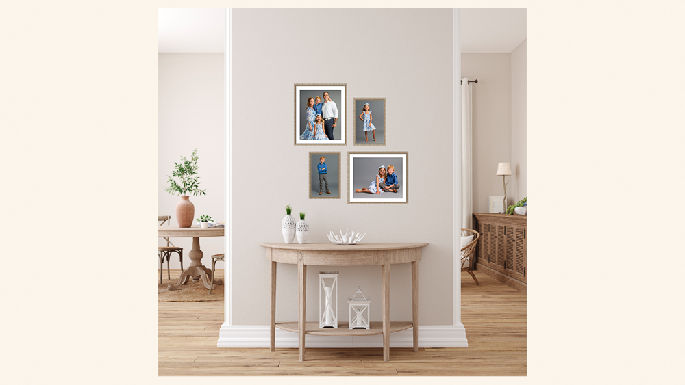 Family portraits displayed on a gallery wall above a wooden console table in a bright, neutral home interior | Lisa Maco Photography