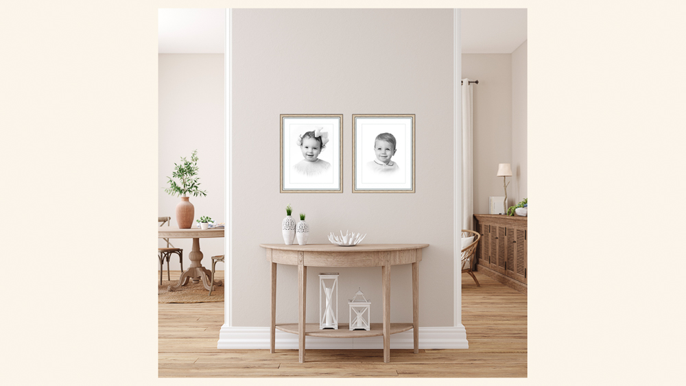 Two framed black and white sibling Heirloom Portraits hang above a light wood console table in a bright foyer with white columns and hardwood floors | Lisa Maco Photography