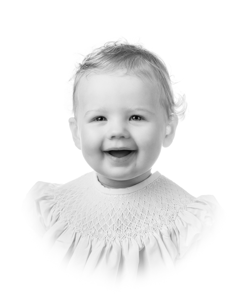 Joyful toddler in a smocked dress during a classic studio portrait session by a DC family photographer