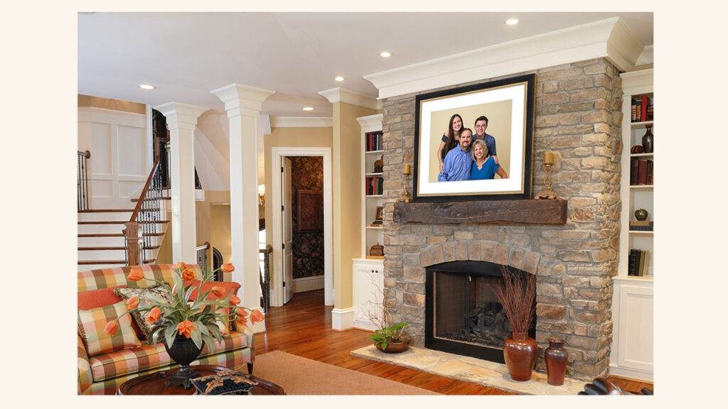 Framed family portrait hanging above a stone fireplace in a bright living room with builtin bookshelves
