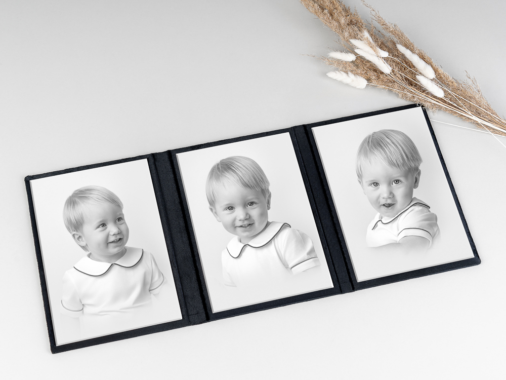 Black and white portrait triptych of a smiling toddler in a collared shirt displayed in a tabletop frame